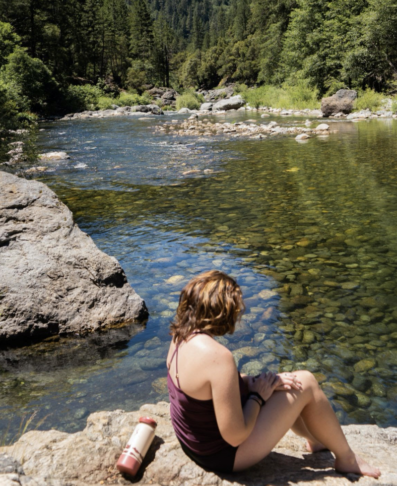 Woman sitting along a stream in Downieville