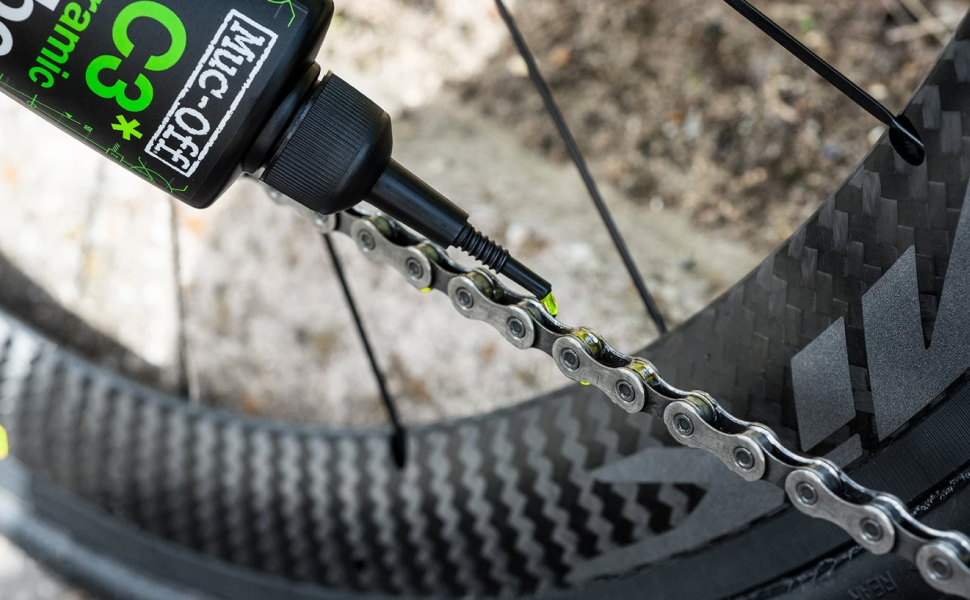 Person lubricating bike chain with Muc-Off oil solution