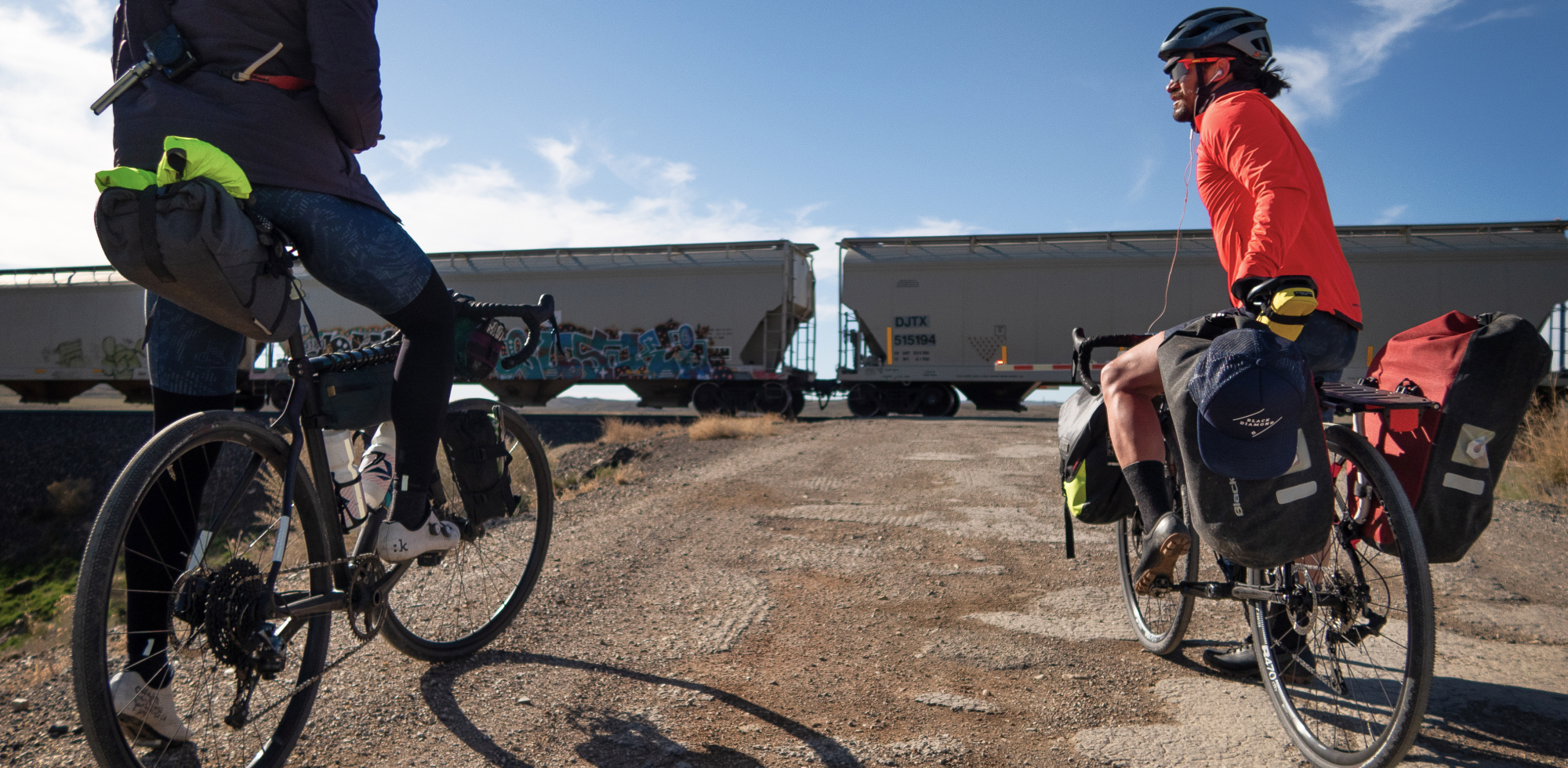 BIKEPACKING BAGS VS TOURING RACKS WITH PANNIERS - bikepackers waiting at railway line
