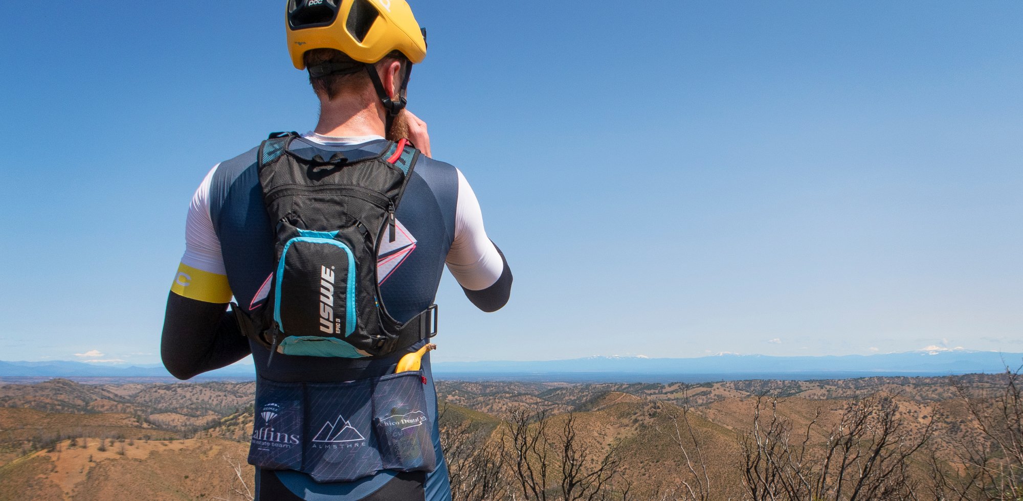 Man overlooking scenic mountain view with USWE hydration pack on 