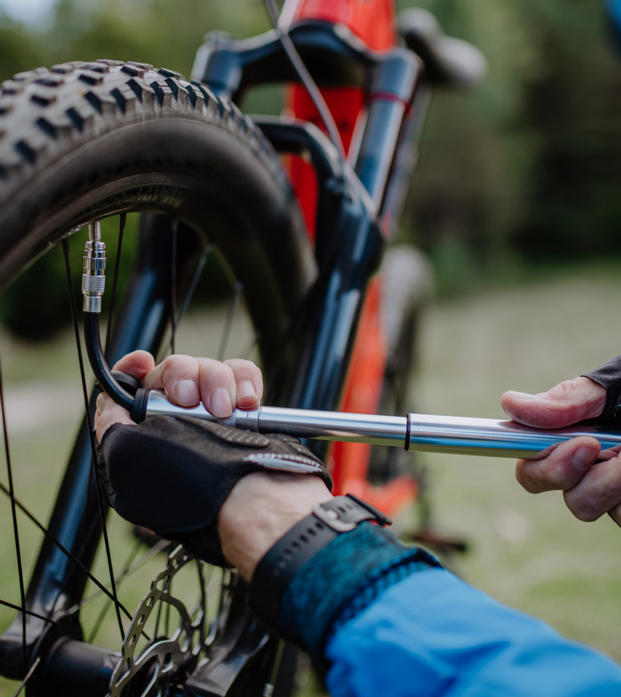 mountain biker using mini pump to inflate tire