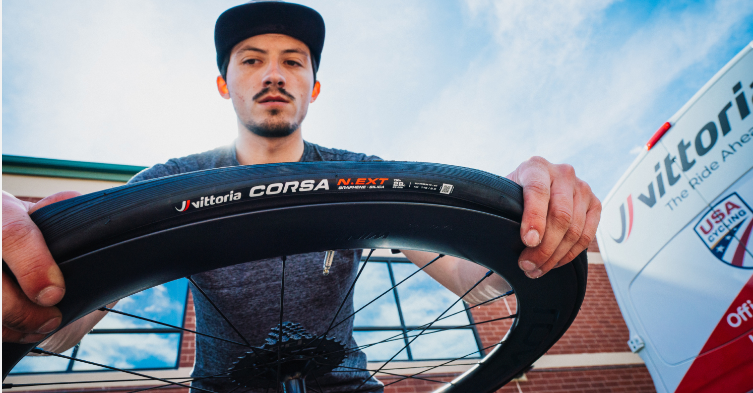 Man installing Vittoria Corsa N.ext tire onto wheel