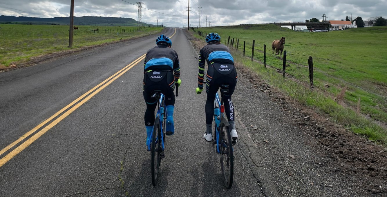 Two road cyclist riding down a road