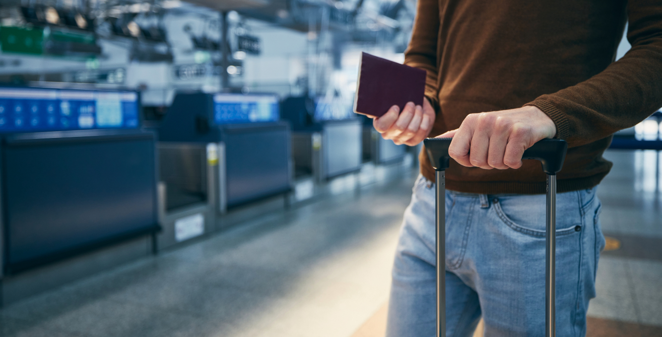 Traveler at an airport terminal with bag and passport