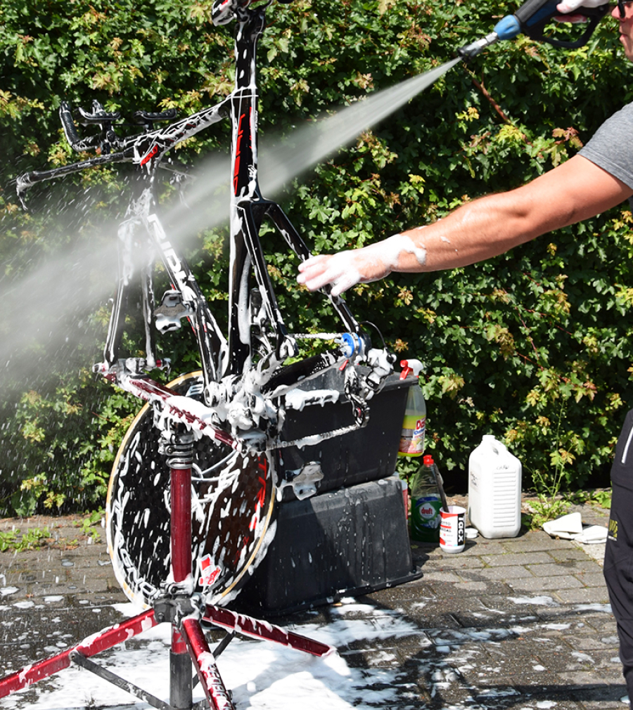 Road bike in repair stand being cleaned with pressure washer