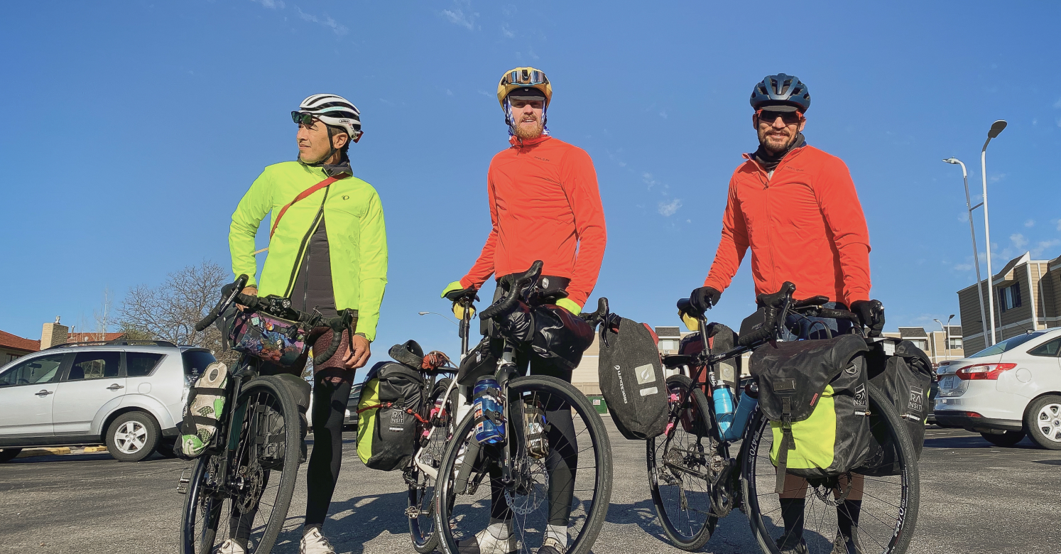 Men standing with gravel bikes carrying camping gear