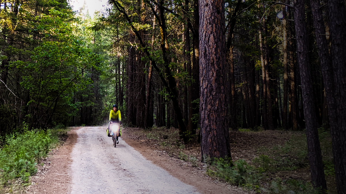 Man riding on gravel road throught woods