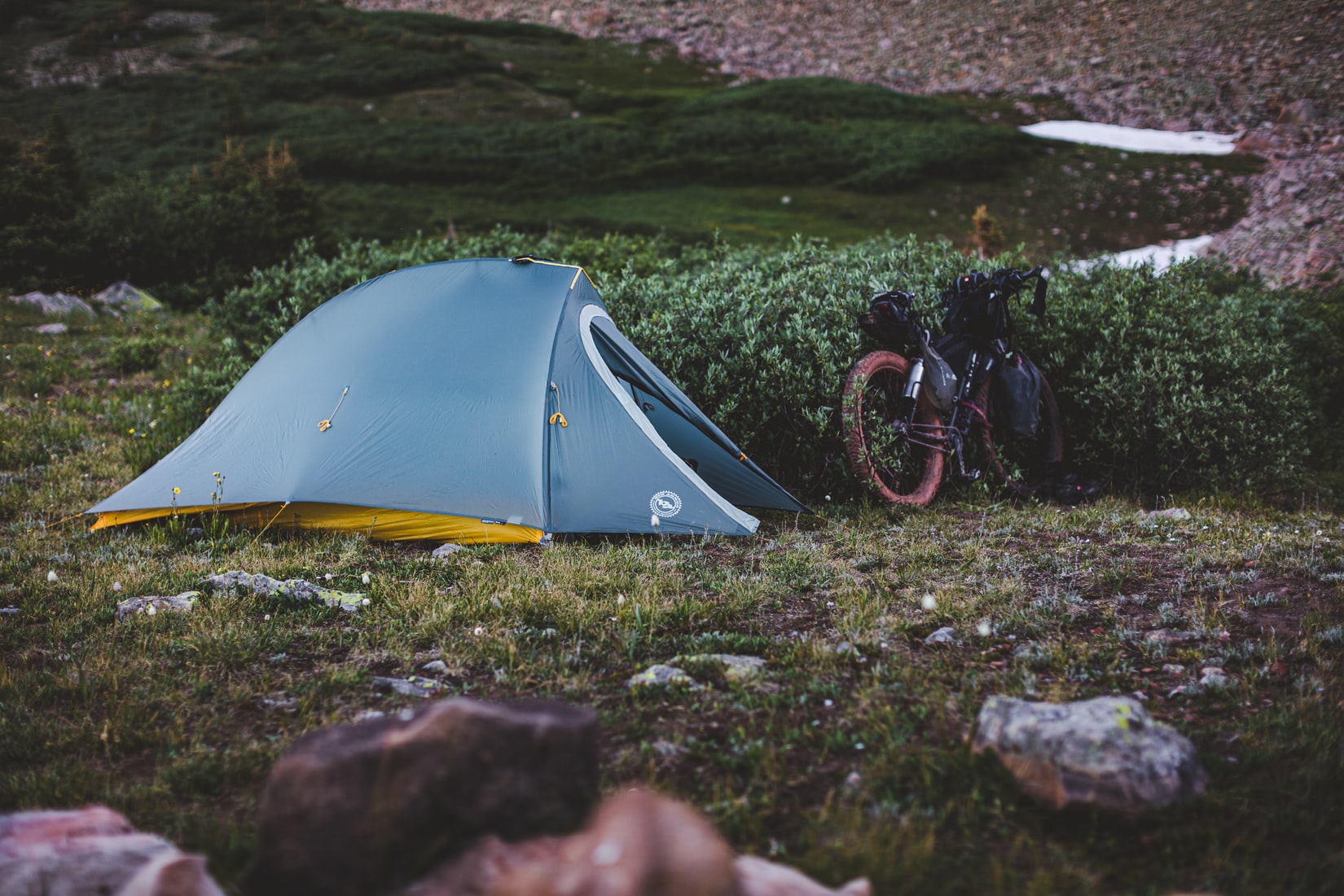 Bikepacker and tent set up in a field