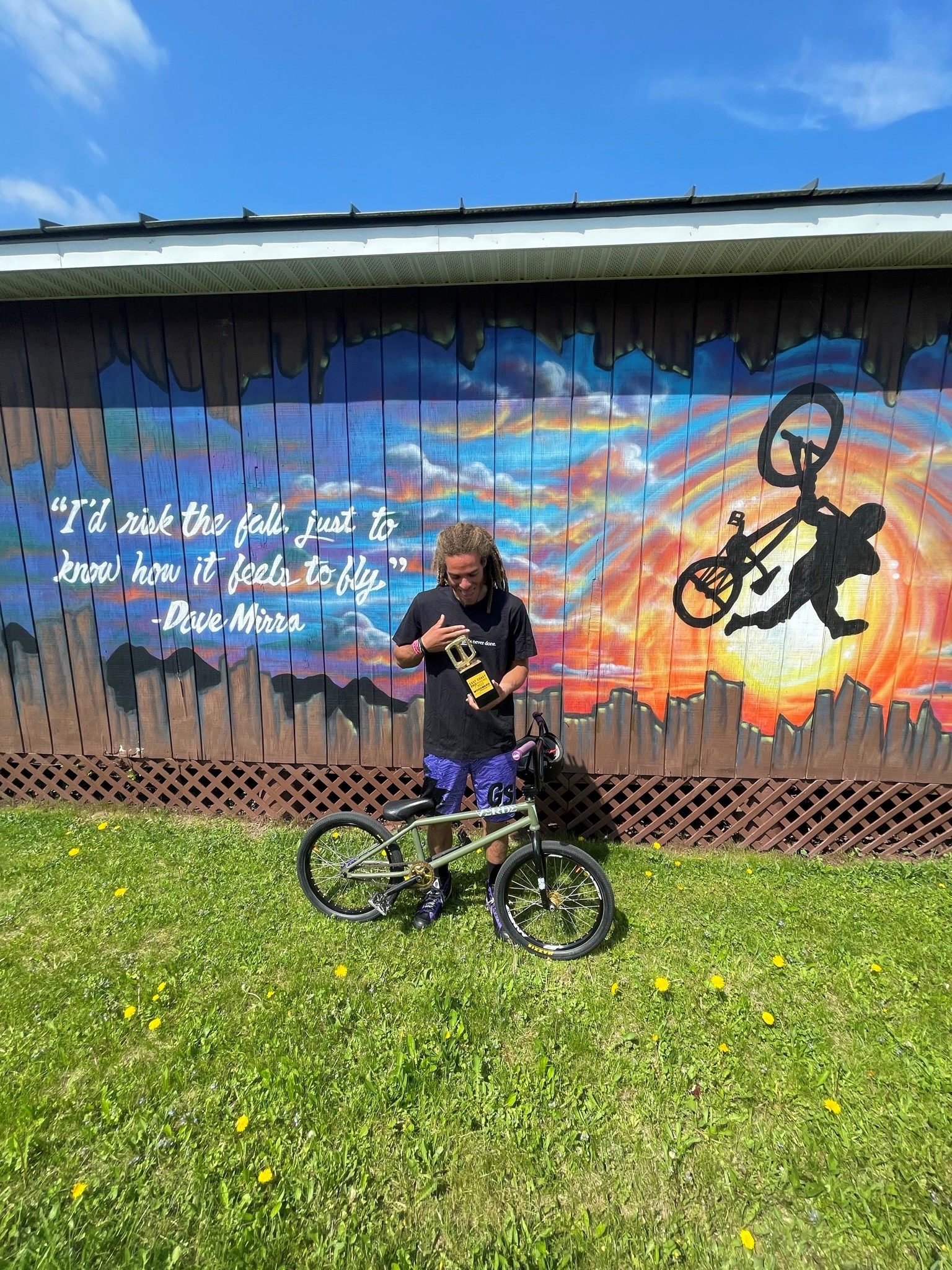 Dan's Comp Flow Team rider Tyler Hill standing in fron of the legendary Dave Mirra murrell at Camp Woodward with the quote 'I'd risk the fall just to know how it feels to fly'